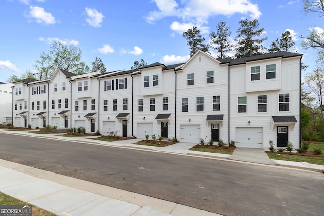 townhome / multi-family property with a garage, a residential view, and driveway