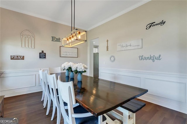 dining room featuring a wainscoted wall, ornamental molding, and dark wood finished floors