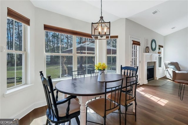 dining space featuring lofted ceiling, dark wood finished floors, visible vents, and a fireplace