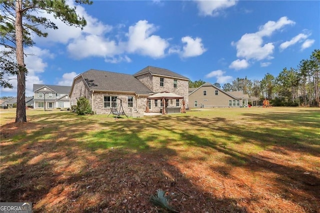 rear view of house featuring a gazebo, a yard, and a playground