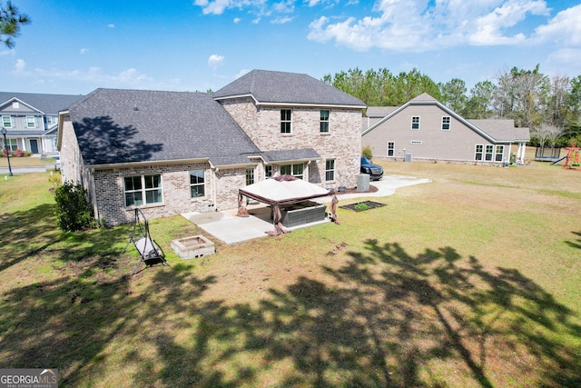 back of house with brick siding, a gazebo, a lawn, roof with shingles, and a patio area