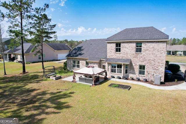 rear view of property featuring a gazebo, brick siding, a garden, and a yard