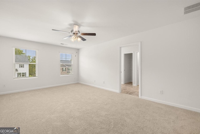 spare room featuring light carpet, ceiling fan, visible vents, and baseboards