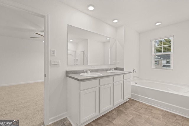 bathroom with a garden tub, a sink, baseboards, and double vanity