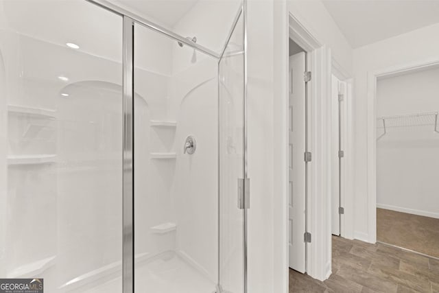 bathroom featuring a shower stall, baseboards, and a walk in closet