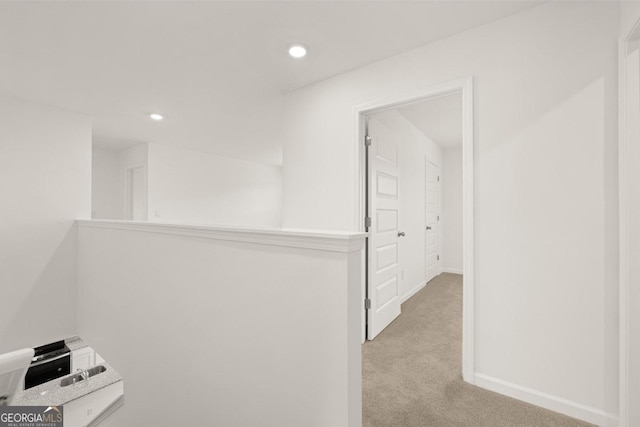 hallway featuring recessed lighting, light colored carpet, and baseboards