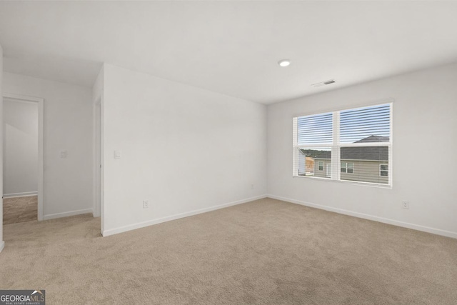 carpeted spare room featuring visible vents and baseboards