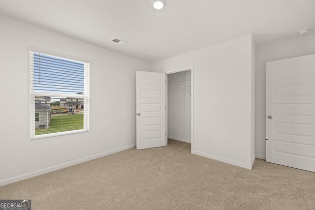 unfurnished bedroom featuring baseboards, a closet, visible vents, and light colored carpet