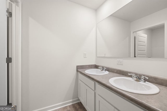 bathroom with double vanity, a sink, baseboards, and wood finished floors