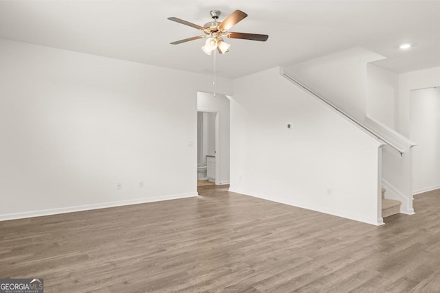 unfurnished living room with baseboards, a ceiling fan, wood finished floors, stairs, and recessed lighting