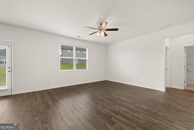 spare room featuring dark wood-style floors, plenty of natural light, and baseboards