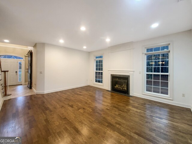 unfurnished living room featuring a fireplace with flush hearth, wood finished floors, and recessed lighting