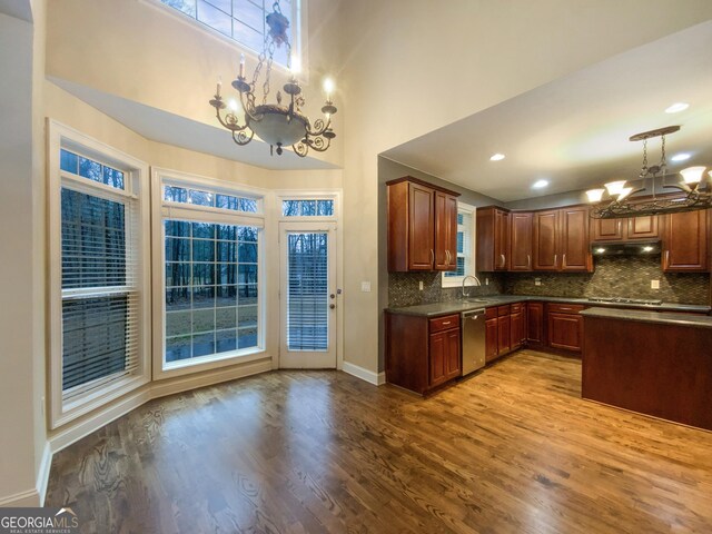 kitchen featuring dark countertops, appliances with stainless steel finishes, under cabinet range hood, a chandelier, and a sink