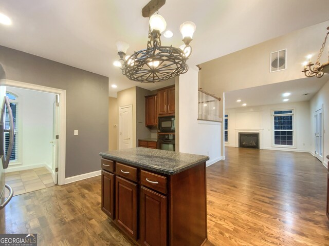 kitchen featuring a chandelier, a fireplace, wood finished floors, visible vents, and black appliances