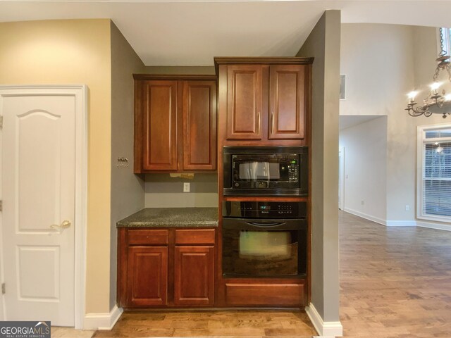 kitchen featuring baseboards, black appliances, light wood-style flooring, and an inviting chandelier