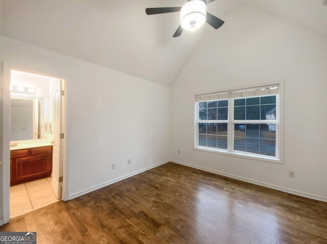 unfurnished bedroom with baseboards, a ceiling fan, connected bathroom, wood finished floors, and high vaulted ceiling