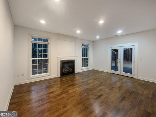 unfurnished living room with recessed lighting, a fireplace with flush hearth, baseboards, french doors, and dark wood finished floors