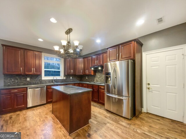 kitchen with visible vents, dark countertops, light wood-style flooring, appliances with stainless steel finishes, and under cabinet range hood