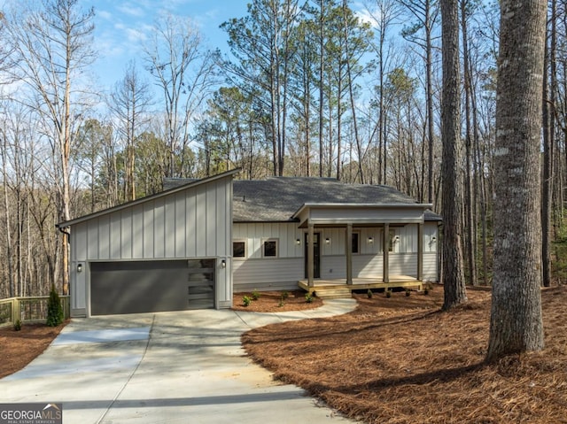 view of front of home with a garage, driveway, a shingled roof, covered porch, and board and batten siding