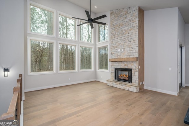544 Lemmon Ln, Ellijay, GA 30540 - unfurnished living room with baseboards, a towering ceiling, ceiling fan, a stone fireplace, and light wood-style floors