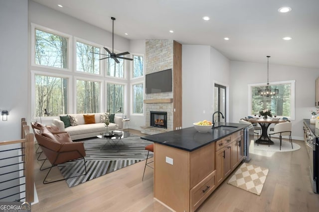 kitchen with light wood-style floors, dark countertops, open floor plan, and a sink