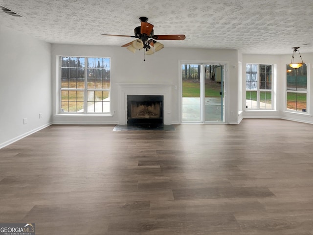 unfurnished living room with dark wood-style floors, a wealth of natural light, and visible vents