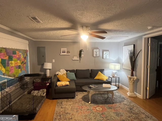 living room featuring visible vents, ornamental molding, wood finished floors, and electric panel