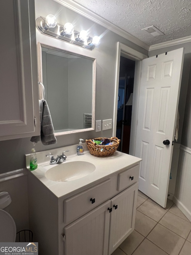 bathroom with a textured ceiling, tile patterned flooring, visible vents, vanity, and ornamental molding