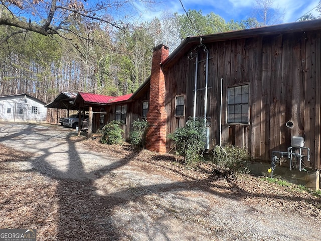 view of home's exterior with dirt driveway and a chimney