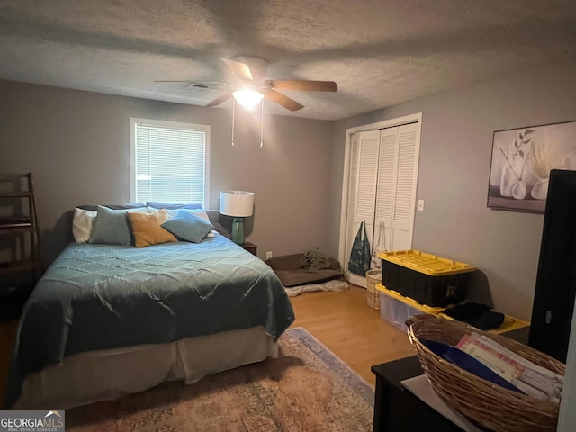 bedroom with a ceiling fan, a closet, a textured ceiling, and light wood finished floors