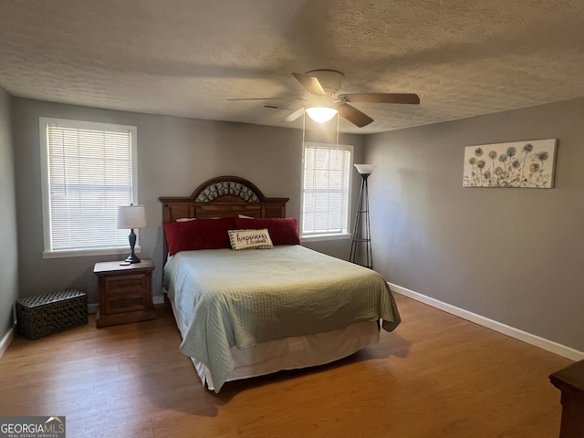 bedroom featuring a textured ceiling, ceiling fan, wood finished floors, and baseboards