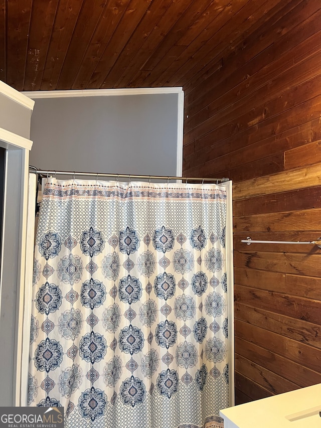 interior details with crown molding, a shower with curtain, wood ceiling, and wooden walls