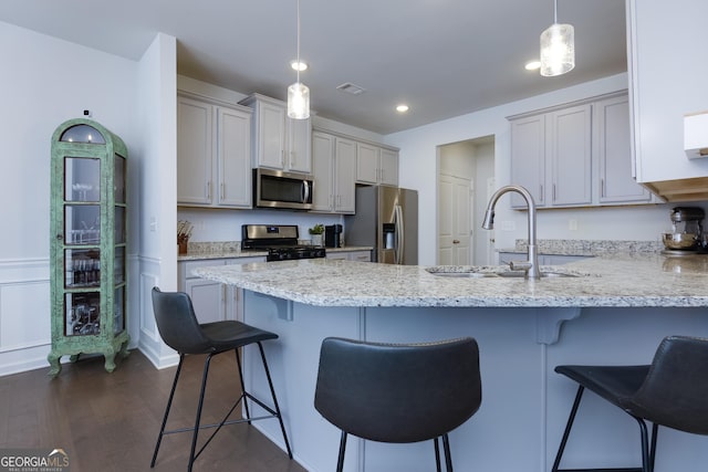 5620 Berney Cir, Powder Springs, GA 30127 - kitchen featuring dark wood finished floors, stainless steel appliances, a sink, a peninsula, and a kitchen bar