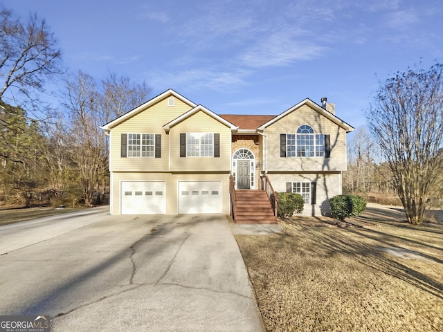 bi-level home featuring a garage, driveway, and a chimney