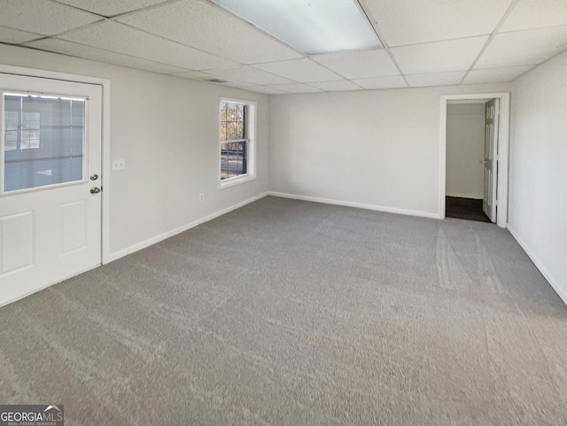 carpeted empty room with a drop ceiling and baseboards