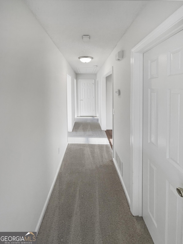 corridor with baseboards, attic access, visible vents, and carpet flooring