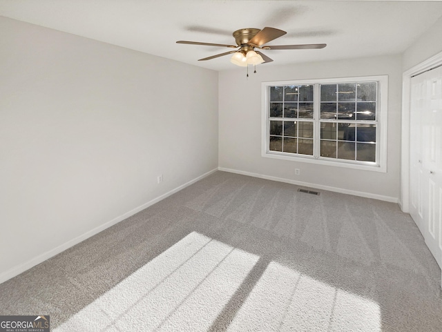 carpeted empty room featuring baseboards, visible vents, and ceiling fan