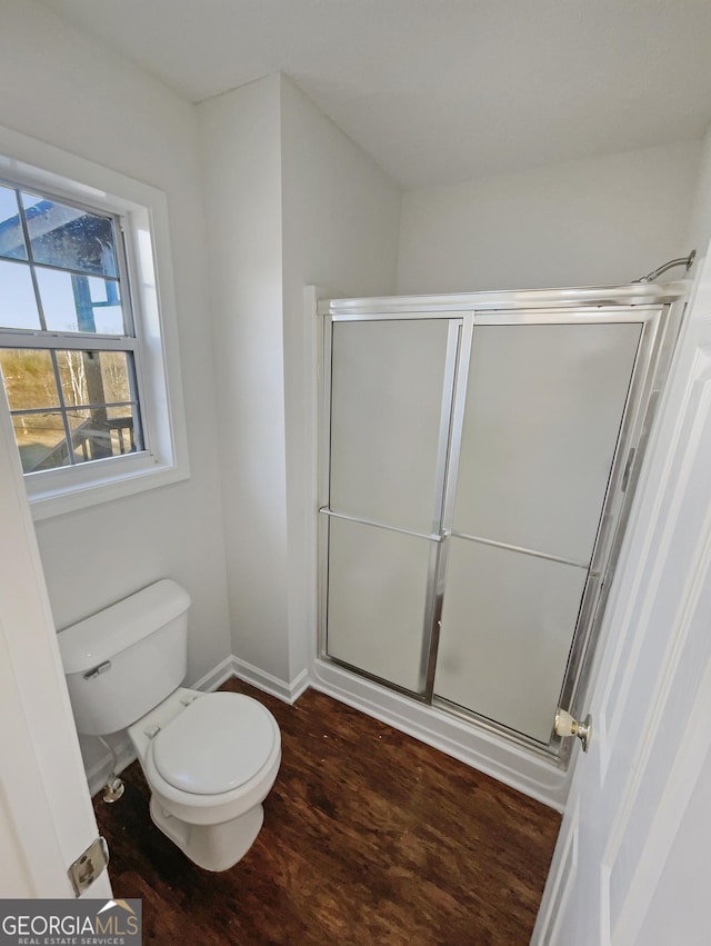 bathroom with baseboards, an enclosed shower, toilet, and wood finished floors