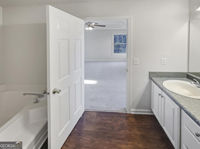 full bathroom with baseboards, a ceiling fan, wood finished floors, a garden tub, and vanity