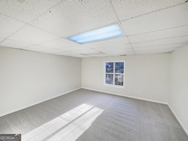 finished below grade area with carpet floors, a drop ceiling, and baseboards