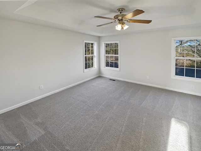 unfurnished room featuring baseboards, visible vents, dark carpet, and a ceiling fan