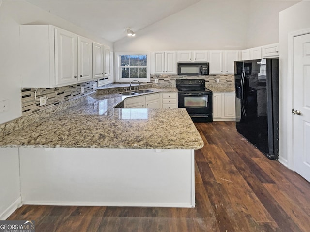 kitchen featuring a peninsula, black appliances, a sink, and light stone countertops