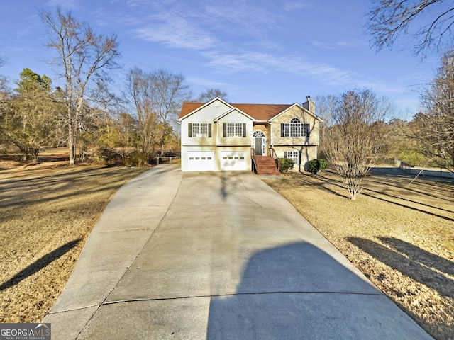 bi-level home featuring driveway, a chimney, and an attached garage