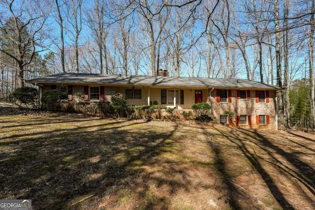 single story home featuring a chimney and a front lawn