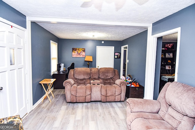 living area featuring baseboards, a textured ceiling, and wood finished floors