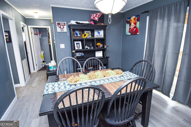 dining space featuring baseboards, a textured ceiling, ornamental molding, and wood finished floors