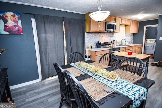 dining space featuring a textured ceiling, baseboards, light wood-style flooring, and crown molding