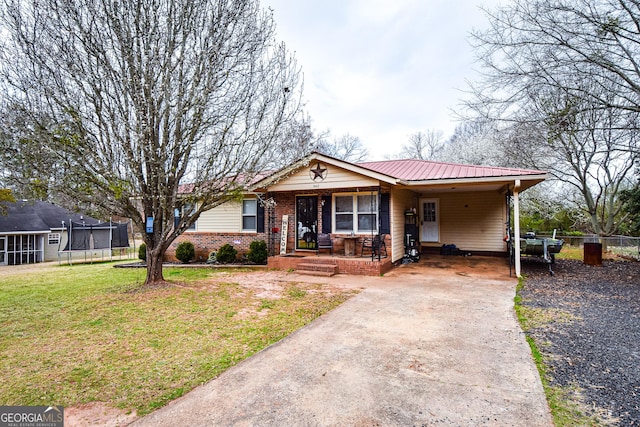 ranch-style house with an attached carport, brick siding, fence, concrete driveway, and a front yard