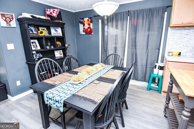 dining space featuring crown molding, light wood-style flooring, and baseboards