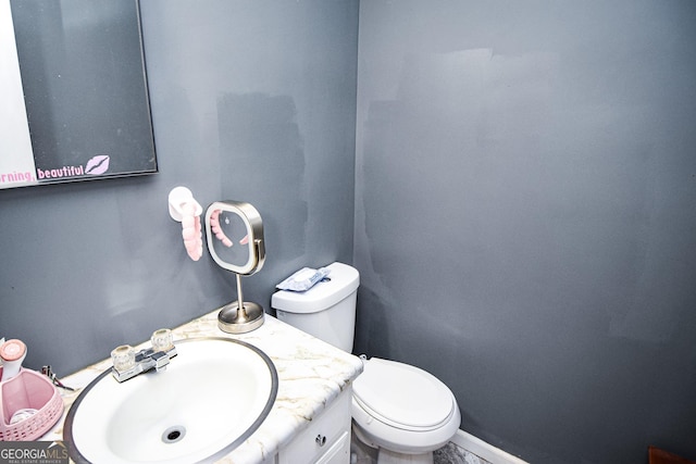 half bath featuring toilet, baseboards, and vanity